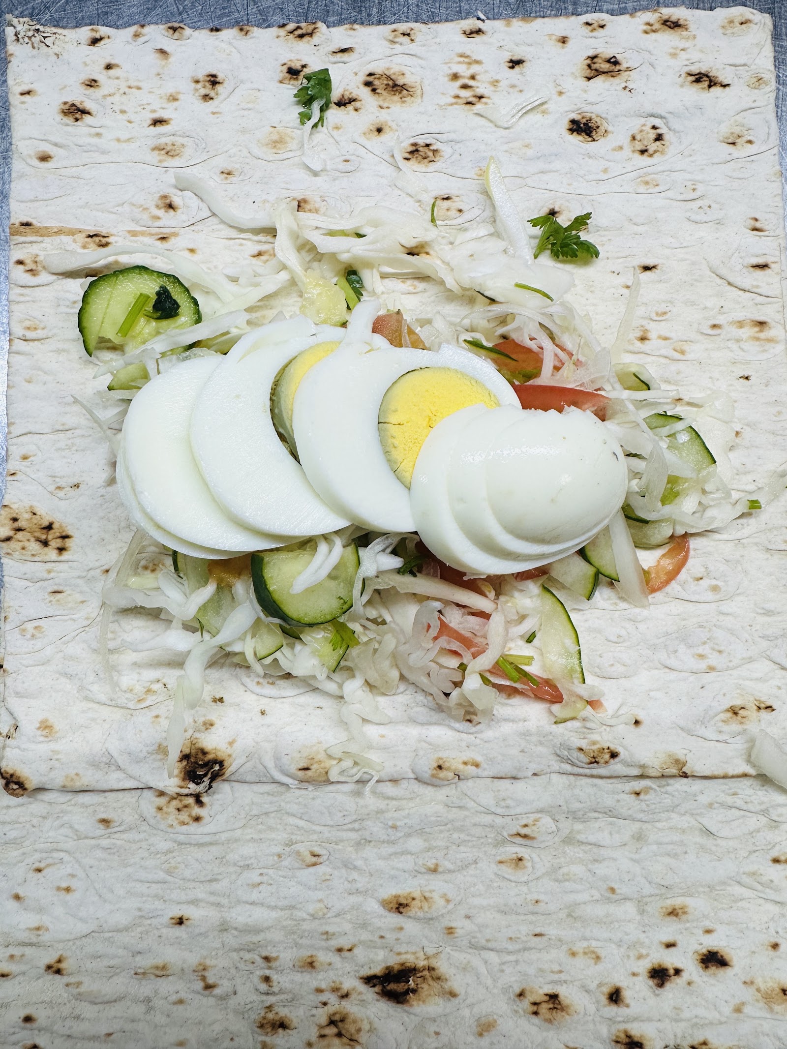 Wrap topped with sliced boiled egg, cabbage, and cucumber